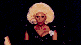 two drag queens are standing next to each other in a dark room with purple lights .