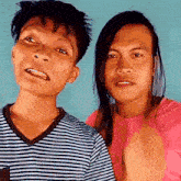 two men with long hair are posing for a picture and one is wearing a striped shirt