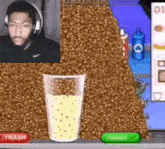a man wearing headphones is playing a video game with a glass of liquid in front of him .