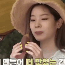 a woman wearing a straw hat and yellow nails is eating a sandwich .