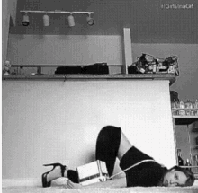 a woman is laying on her stomach on the floor in a kitchen holding a box .