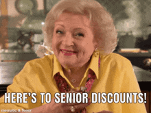 an elderly woman in a yellow shirt is smiling and says here 's to senior discounts