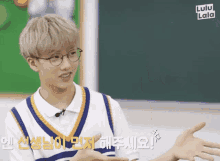 a young man wearing glasses is talking to someone in a classroom with lulu lala written in the corner