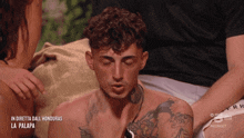 a man with a tattoo on his chest is sitting on a couch with his eyes closed and the caption in diretta dall honduras