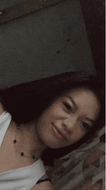 a girl in a white tank top is smiling and looking at the camera