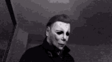 a black and white photo of a person wearing a mask holding a remote control .