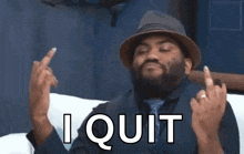 a man in a hat and tie is sitting on a couch giving the middle finger .
