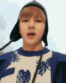 a close up of a person wearing a hat and a blue sweater