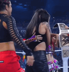 two women are hugging each other in a wrestling ring .
