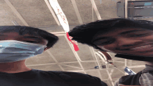 a man wearing a mask smiles next to another man wearing a mask