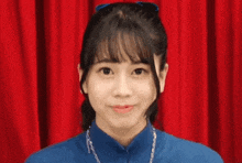 a young woman in a blue shirt is making a heart shape with her hand .