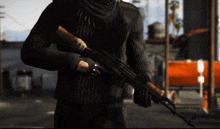 a man in a black sweater holds a rifle