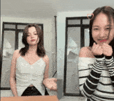 a woman in a white tank top and a woman in a black and white striped top
