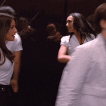 a woman in a white shirt stands in a crowd