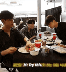 two men are sitting at a table with plates of food and drinks .