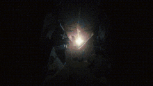 a close up of a person 's face with a light coming out of it in a dark room .