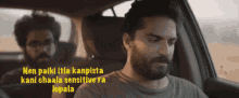 a man with a beard is sitting in the driver 's seat of a car next to another man with a beard