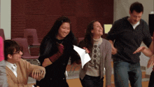 a group of people are dancing in a room with chairs
