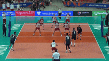 a group of volleyball players are playing on a court with a sign that says volleyball world on it