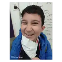 a boy wearing a face mask is smiling in front of a white board that says ' spag ' on it