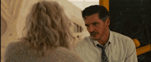 a man in a white shirt and tie talks to a woman