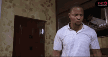a man in a white striped shirt is standing in front of a door that says tnco