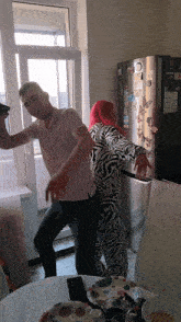a man and woman dancing in front of an lg fridge