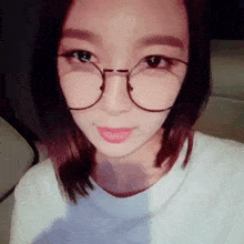 a close up of a woman wearing glasses and a white t-shirt .