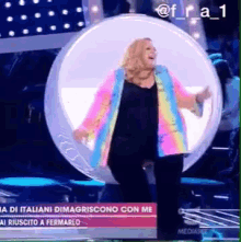 a woman in a colorful jacket is standing in a circle on a stage ..