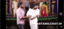 a group of men are standing next to each other in front of a group of people and a sign that says tamilchat.in on it