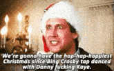 a man wearing a santa hat is talking about christmas while dancing with danny fucking kaye .