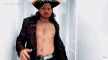 a shirtless man in a pirate hat and jacket is standing in a hallway .