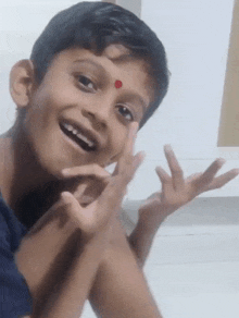 a young boy with a red dot on his forehead smiles for the camera