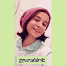 a girl wearing a pink hat and a blue shirt is smiling and making a funny face .