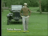 a man in a hat is standing in front of a car that says falha nossa