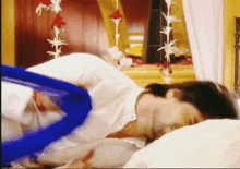 a woman in a white shirt is laying on a bed with a blue object in her hand