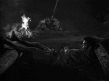 a man laying in front of a fire with his feet up