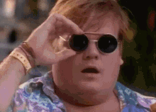 a fat man wearing sunglasses is looking through his glasses .