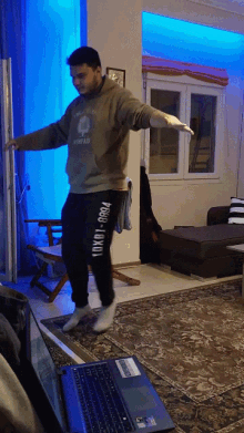 a man dancing in a living room with a laptop in front of him that says lenovo