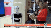 a woman in a red jacket is talking to a robot on a tv show