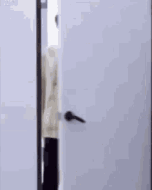 a man in a white sweater is standing in a doorway and looking out .