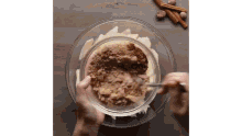 a person is stirring a bowl of food with a spoon .