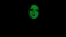 a woman 's face is projected on a green screen in the dark