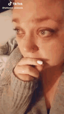 a woman with a nose ring is crying while holding her hand to her mouth .