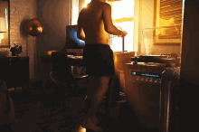 a shirtless man is standing in front of a computer in a dark room