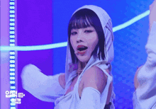 a woman wearing a white hooded top is dancing on a stage