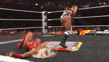 a woman is laying on the ground in a wrestling ring while another wrestler kicks her