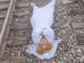 a woman in a white dress is tied to a train track