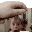 a close up of a person 's hand reaching out towards a child 's face .