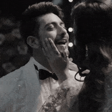 a man in a tuxedo and bow tie is being kissed by a woman